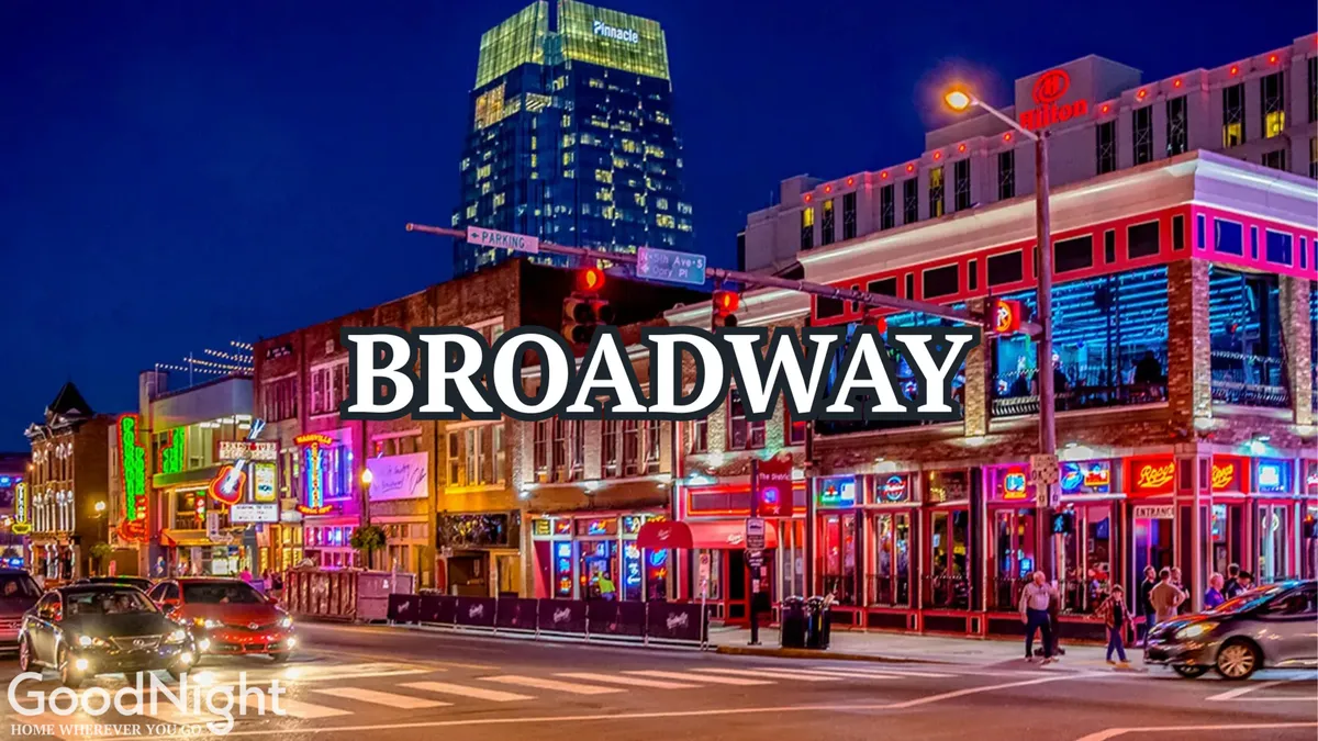 A vibrant Nashville street scene at night featuring illuminated signs, a busy street lined with restaurants and music venues, and crowds of people enjoying the city’s nightlife. A modern skyscraper rises in the background, enhancing the sense of urban excitement.